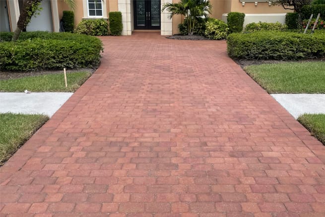 Elegant Styles Power Wash technician pressure washing a sidewalk outside a Naples, Florida commercial property