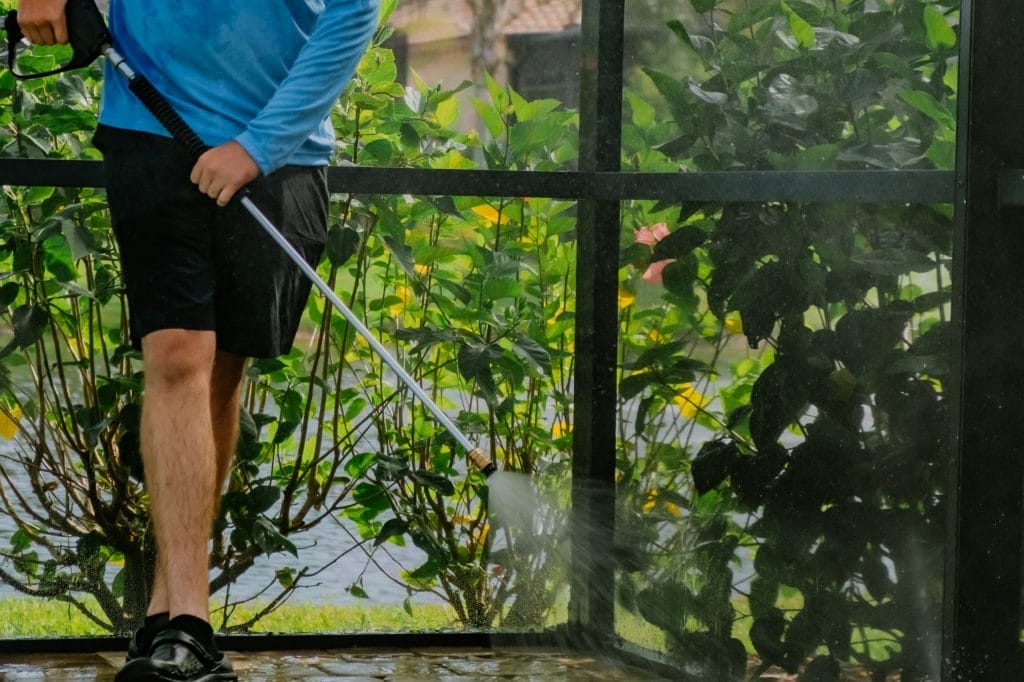 Technician performing soft washing on luxury home exterior in Naples FL.